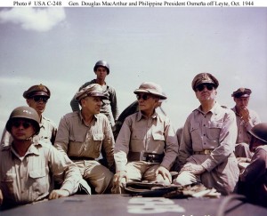 Philippine President Sergio Osmeña (center) and General Douglas MacArthur (right) on board a landing craft en route to the Leyte landing beaches, October 20, 1944. At left are Lieutenant General George C. Kenney and Lieutenant General Richard K. Sutherland. At the extreme right, with his head turned toward MacArthur, is Brigadier General Carlos Romulo. In the front row with two stars on his battle helmet, is Major General Basilio J. Valdes, Chief of Staff of the Philippine Army and Secretary of National Defense in the Osmeña War Cabinet. Photograph from the Army Signal Corps Collection in the U.S. National Archives.